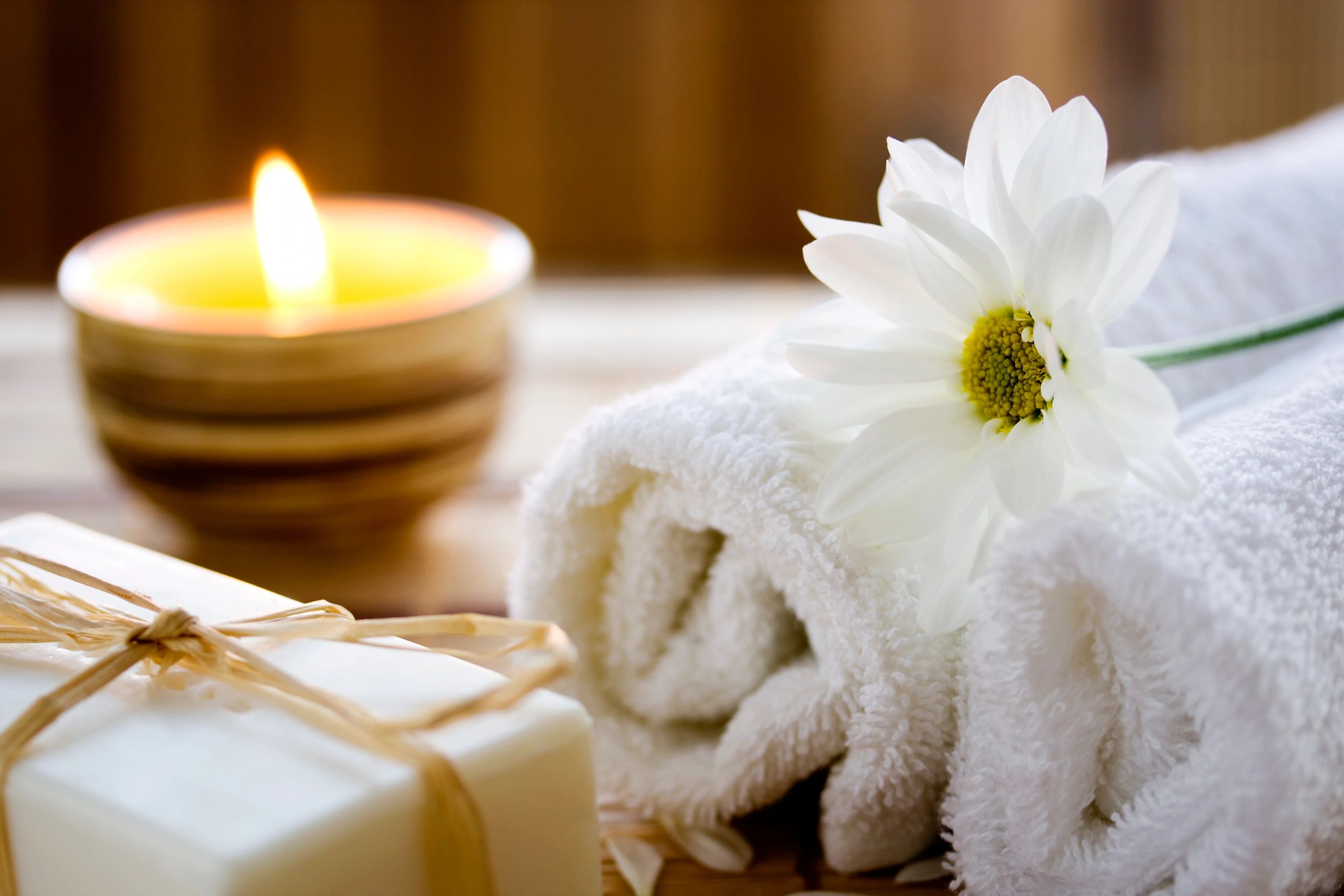 Relaxing spa setting with candle, towel, flower, and soap.