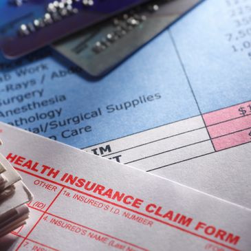 Close-up of a health insurance claim form and a medical bill with a credit card.