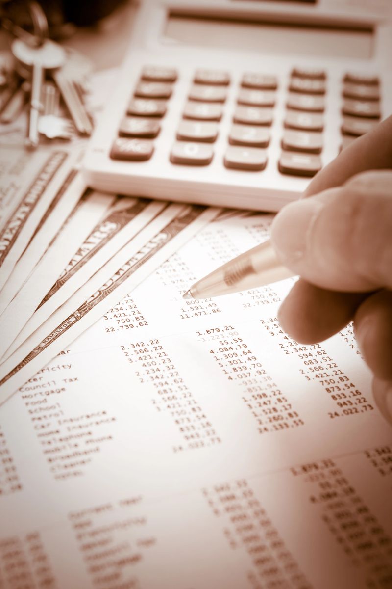 Hands checking figures on a financial document.