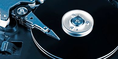 Close-up of an open hard drive showing the spinning disk and read/write arm.