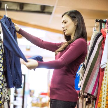 Woman examining a blue shirt on a hanger in a clothing store.