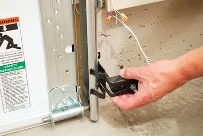 Faulty garage door safety sensors: misaligned photoelectric beams near the floor, not working.

