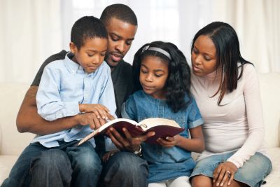 Family reading a book together on a couch.
