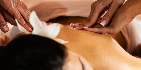 Close-up of a person receiving a relaxing back massage with flower decoration.