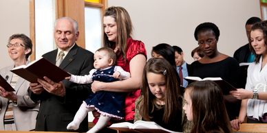 Diverse group of people singing from hymnals in a church.