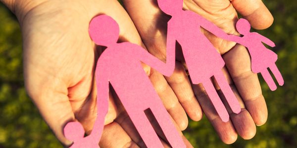 Hands holding paper cutouts of a family of four.