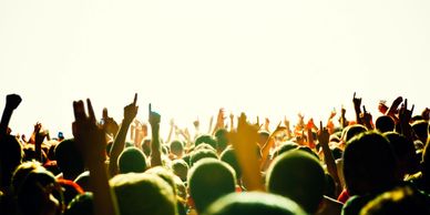 Crowd at a concert raising hands in excitement.