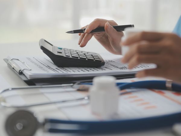 Medical professional calculating medication dosage using a calculator and documents.