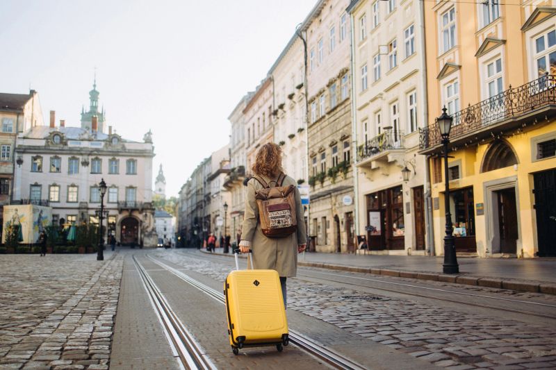 A beautiful and cheerful woman is captured as she walks along a charming, ancient European street during the autumn season