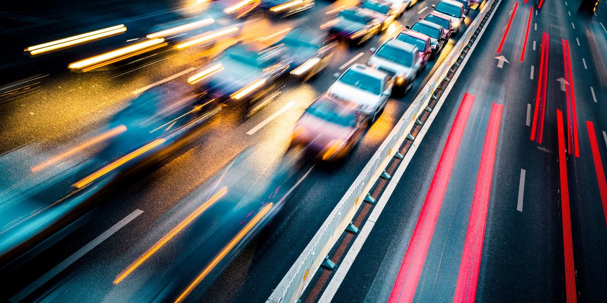 Blurred lights of fast-moving traffic on a busy city road at night.