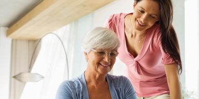 Older woman and younger woman smiling together indoors.