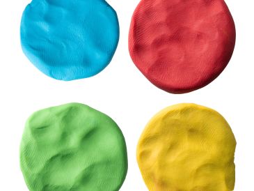 Four colorful flattened balls of clay in blue, red, green, and yellow.