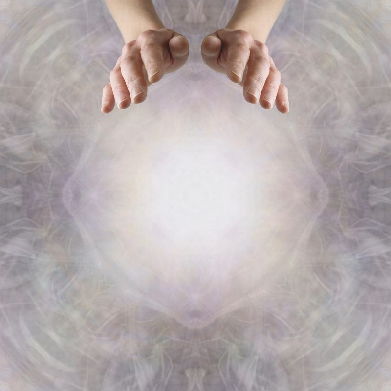 mature woman's hands positioned for healing  against asymmetrical wispy delicate ethereal energy field background with copy space