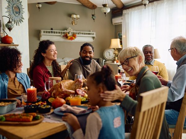 A diverse family enjoying a festive meal together at a warmly decorated table.