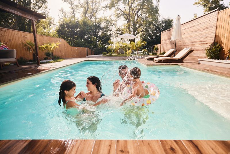 Carefree parents and their kids having fun during summer day in the swimming pool. Copy space.