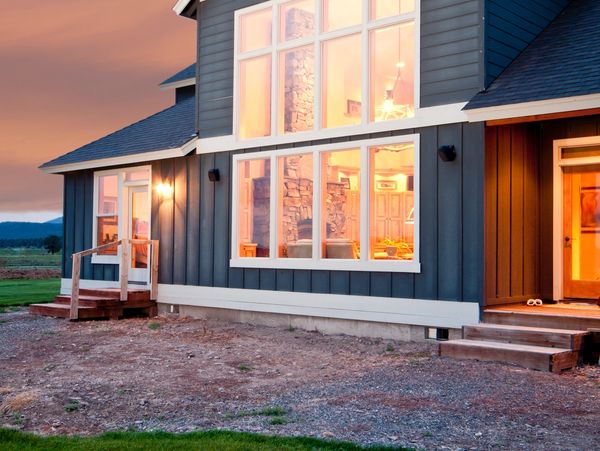 Modern cozy house with large windows glowing at sunset.