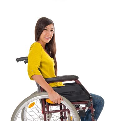 Smiling woman sitting in a wheelchair wearing a yellow top and jeans.