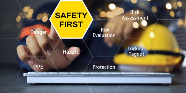 Safety first concept with keywords like hazard, PPE, and risk assessment over a keyboard.