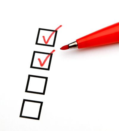 Checklist with two red checkmarks and pen.