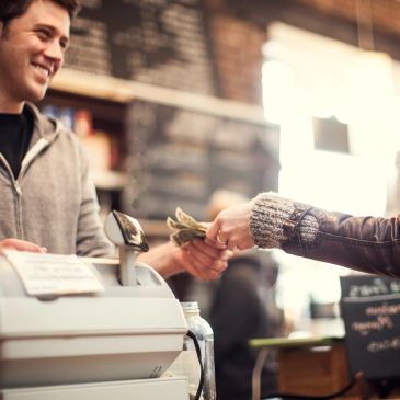 Customer pays cashier with cash at a counter.