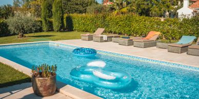 Sunny backyard pool with loungers and inflatables.