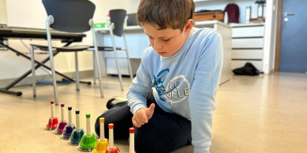 Boy playing with colorful musical bells.