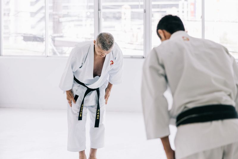 Japanese man demonstrates their reverence for karate by bowing with grace and unity before commencing their practice.