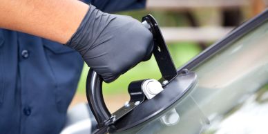 Person using a tool to replace a car windshield.