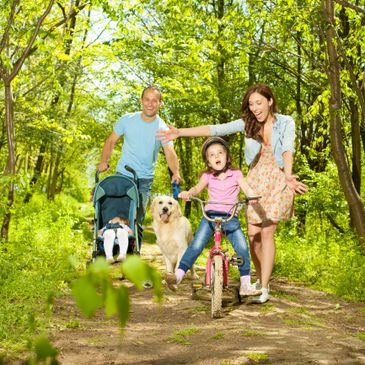 Family enjoying a bike ride and walk in a sunny forest path.
