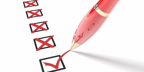 Red pen marking checkboxes with crosses and one checkmark on white paper.