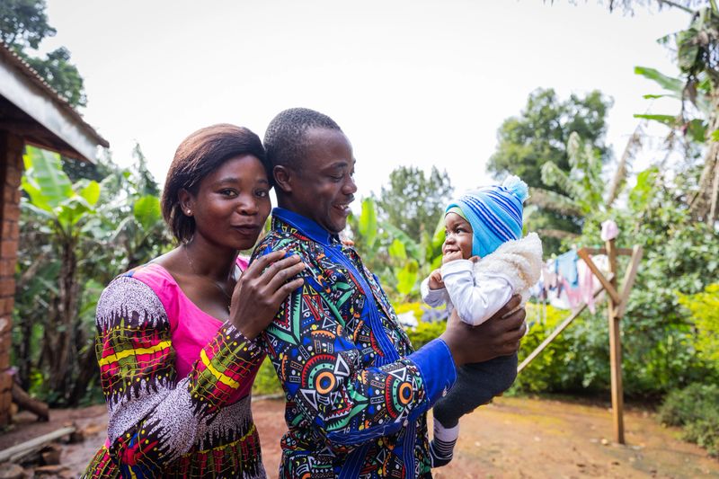 Smiling young father standing in the courtyard affectionately playing with their cute baby.