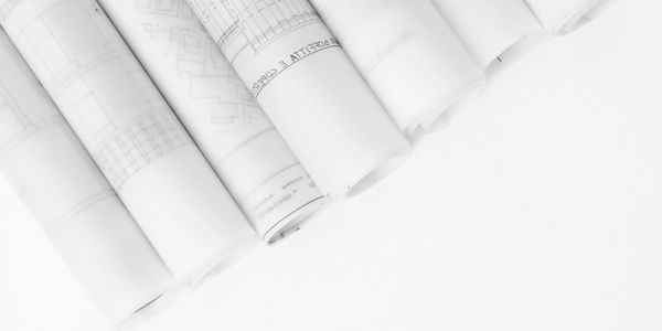 Rolled architectural blueprints arranged in a neat row on a white surface.