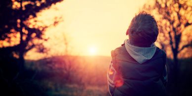 A child watches a warm sunset in a peaceful outdoor setting.