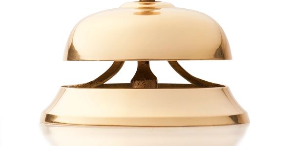 A shiny gold service bell on a white background.