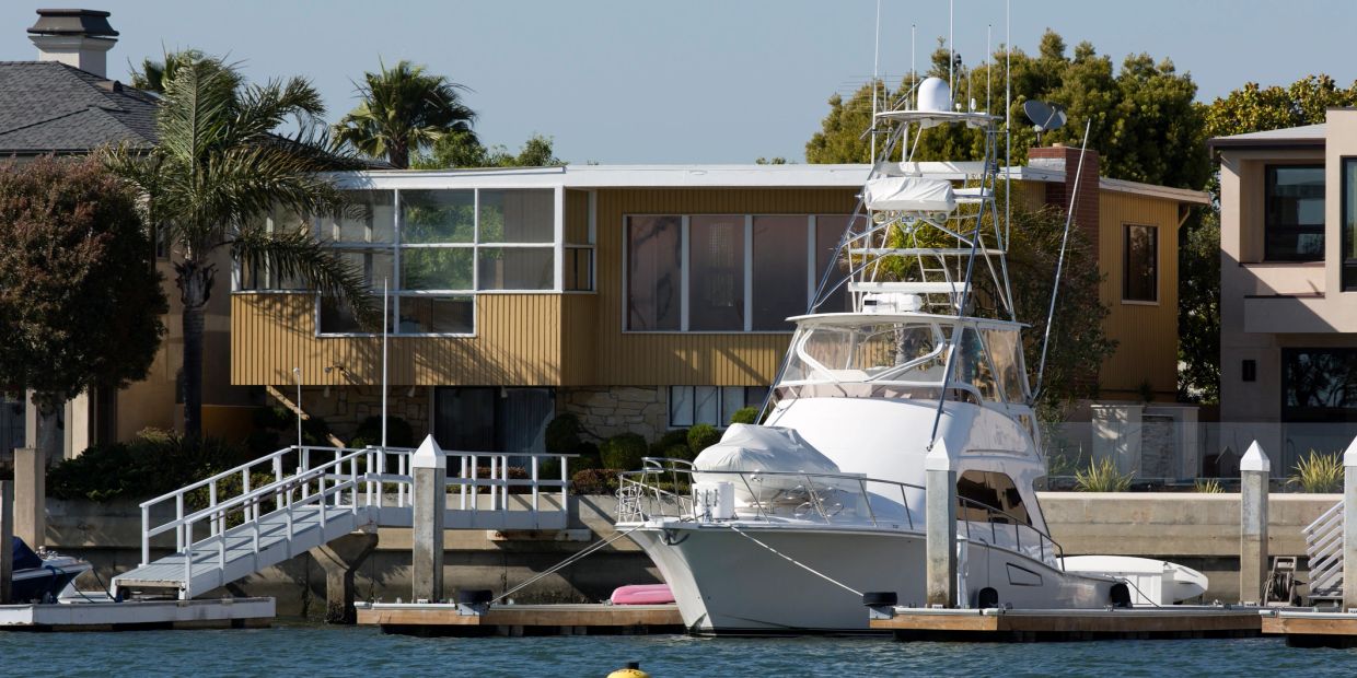 White yacht docked by a waterfront house.