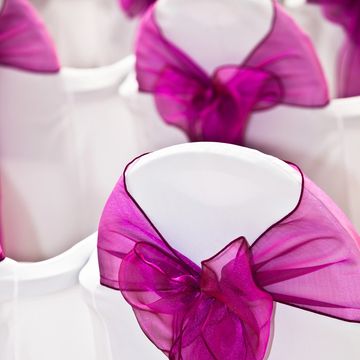 White chairs decorated with purple organza bows.