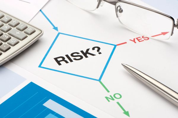 Close-up of a risk assessment flowchart with a calculator, pen, and glasses.