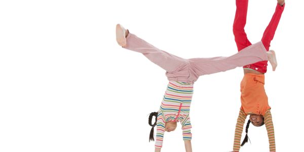 Two children doing handstands with joyful expressions.