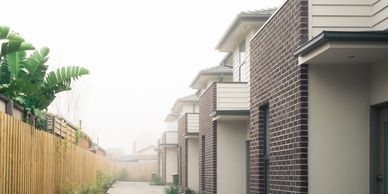 Row of modern townhouses along a narrow driveway on a foggy day.