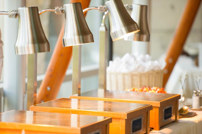 Illuminated heat lamps over induction warmers on a buffet