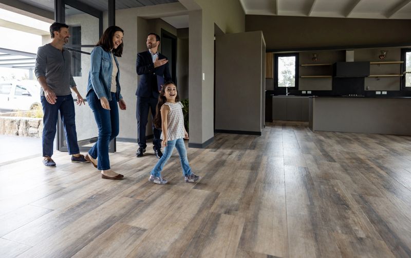 Real estate agent showing a house for sale to a happy Latin American family - home ownership concepts