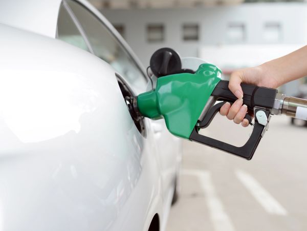 Hand fueling a white car at a gas station.
