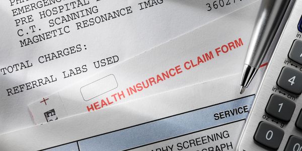 Health insurance claim form with medical documents and pen.