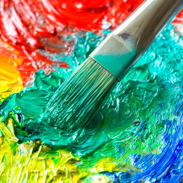 Brush blending vibrant green paint among red, yellow, and blue colors.