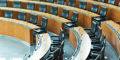 Sala de conferencias vacía con filas curvas de sillas.
