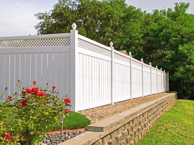 Beautiful white vinyl fence in back yard with nice landscaping in the foreground and background