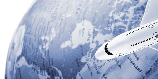 A white airplane model flying over a blue globe focusing on Greenland.