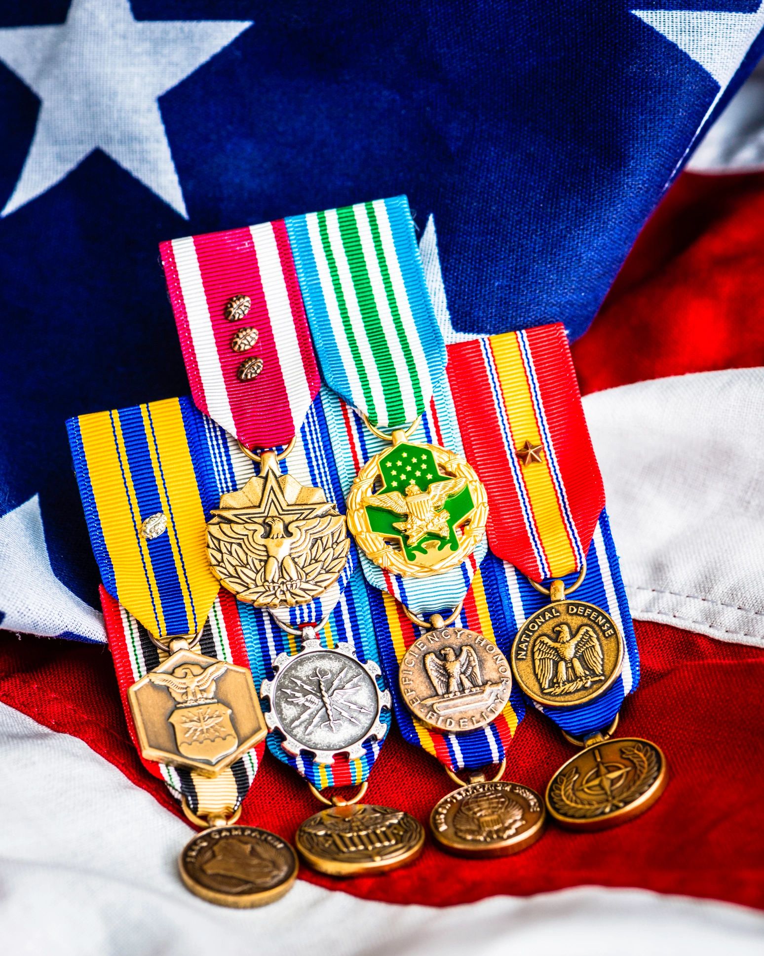 A collection of military medals displayed on an American flag.
