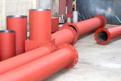 Plusieurs tuyaux métalliques rouges dans un entrepôt.