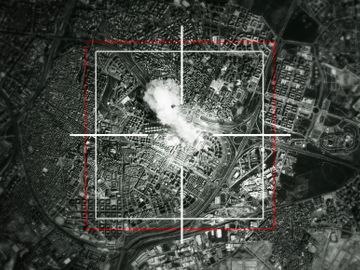 Aerial black and white photo with a crosshair overlay targeting a city area.